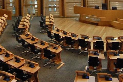 An auditorium with wooden desks arranged in a semi-circle